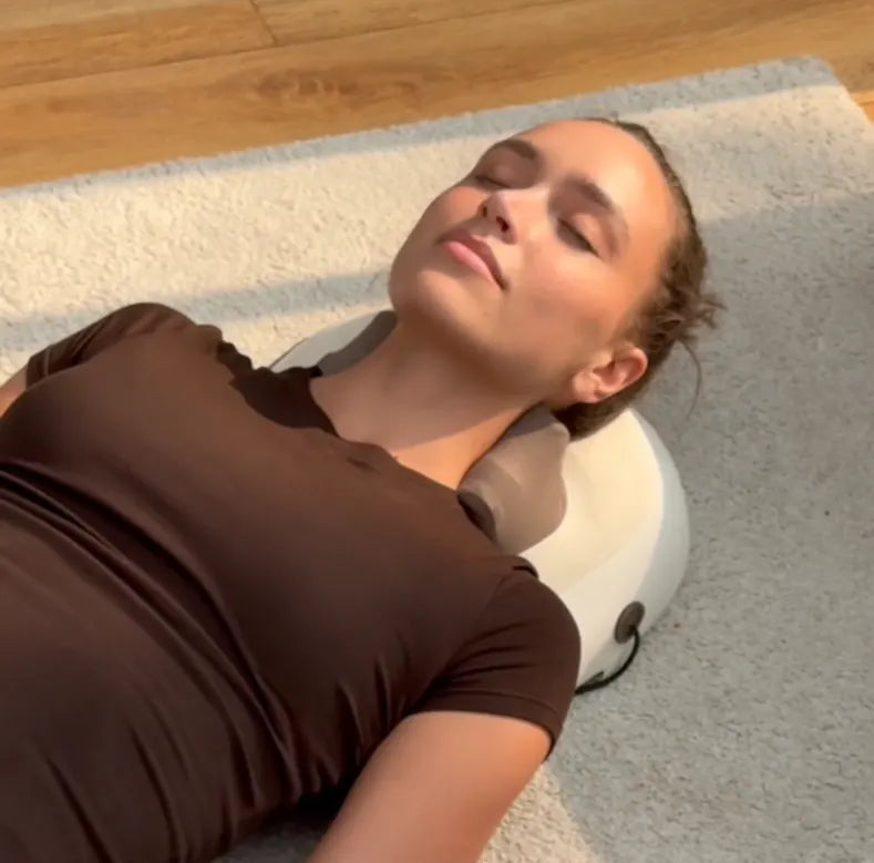 Woman lying back relaxed with the Hizoo massager working along her neck