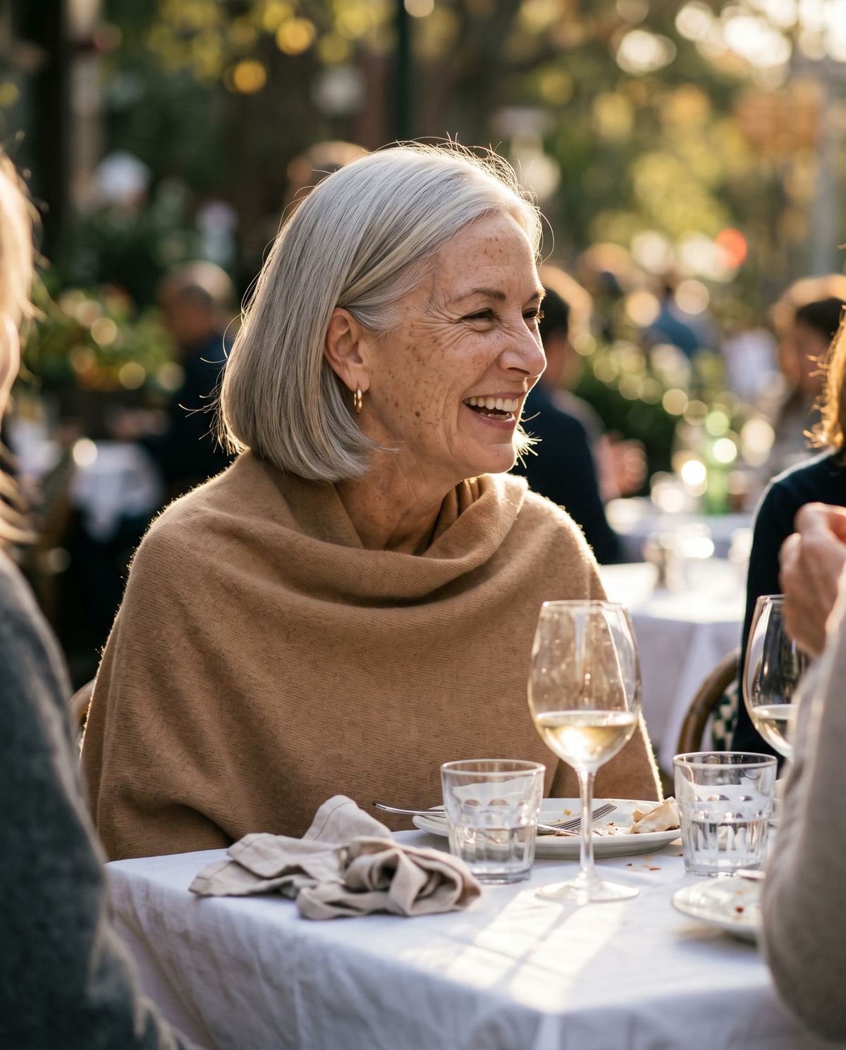 Woman around 60 laughing with friends at a cafe